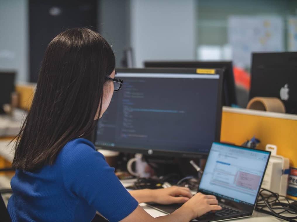 Alt text: A woman in an office researching technology expense management on her computer